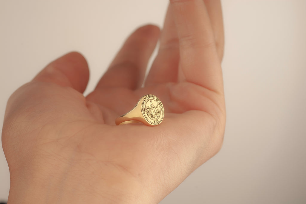 Custom school emblem engraved on an oval graduation ring