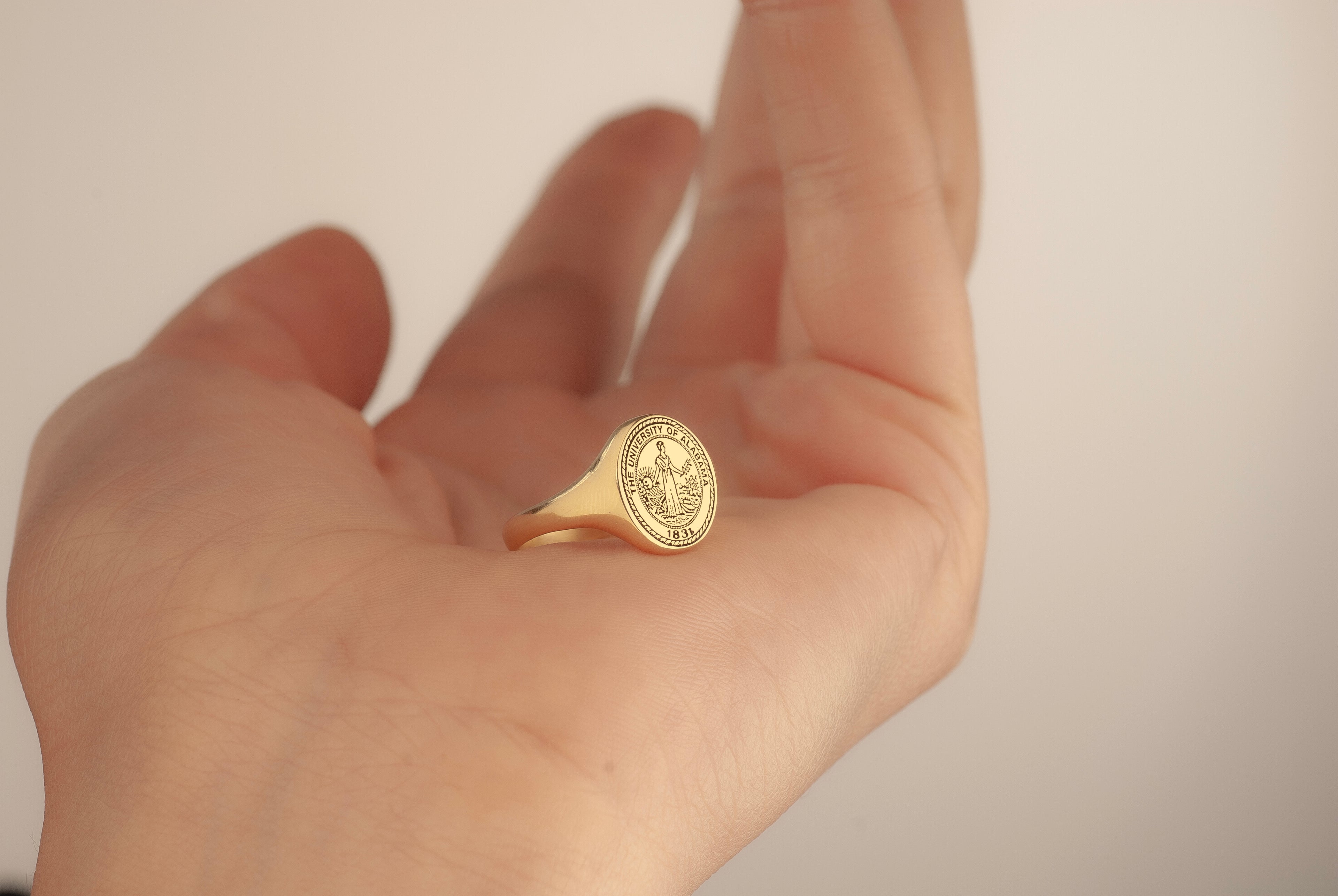 Custom school emblem engraved on an oval graduation ring