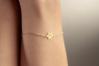 Gold dog paw name bracelet worn on a woman’s wrist