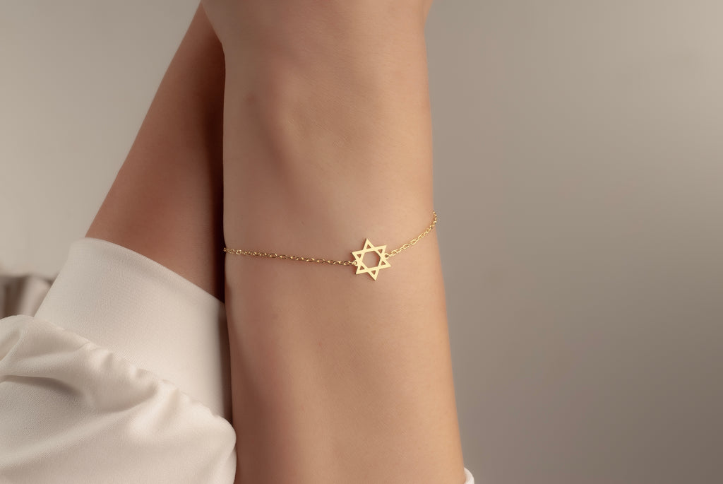 Gold Magen David bracelet worn on a woman’s wrist