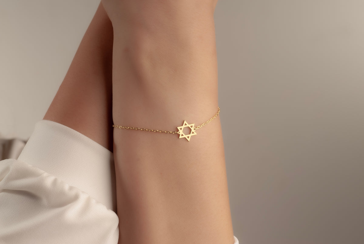Gold Magen David bracelet worn on a woman’s wrist