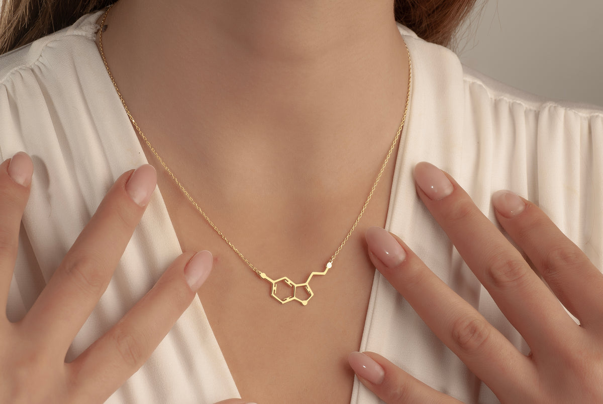 Dainty serotonin molecule necklace worn by a woman
