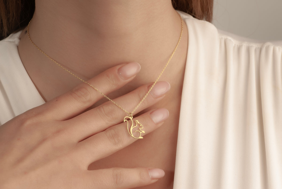 Gold squirrel pendant necklace worn by a woman